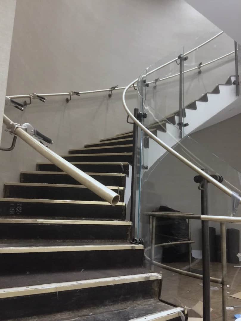 Bank of Canada, Ottawa: Curved stair seen from the bottom step, with glass guardrail panels and a handrail still in its protective wrap