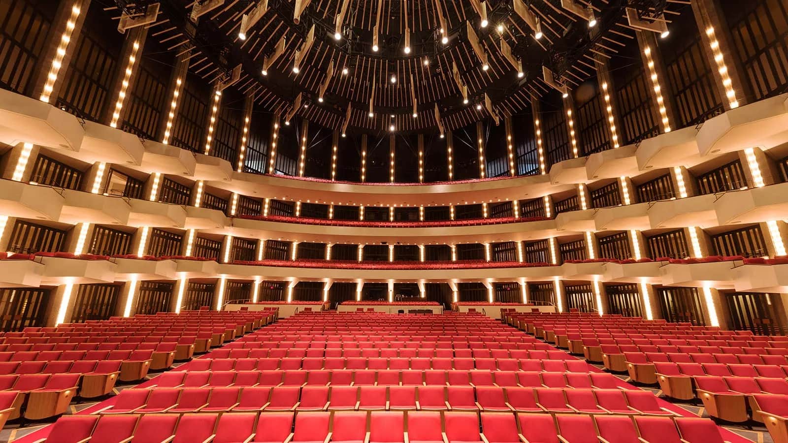 National Arts Centre (NAC), Ottawa: Wide view of the auditorium under its suspended lighting ceiling, with curved balcony tiers and rows of red seats