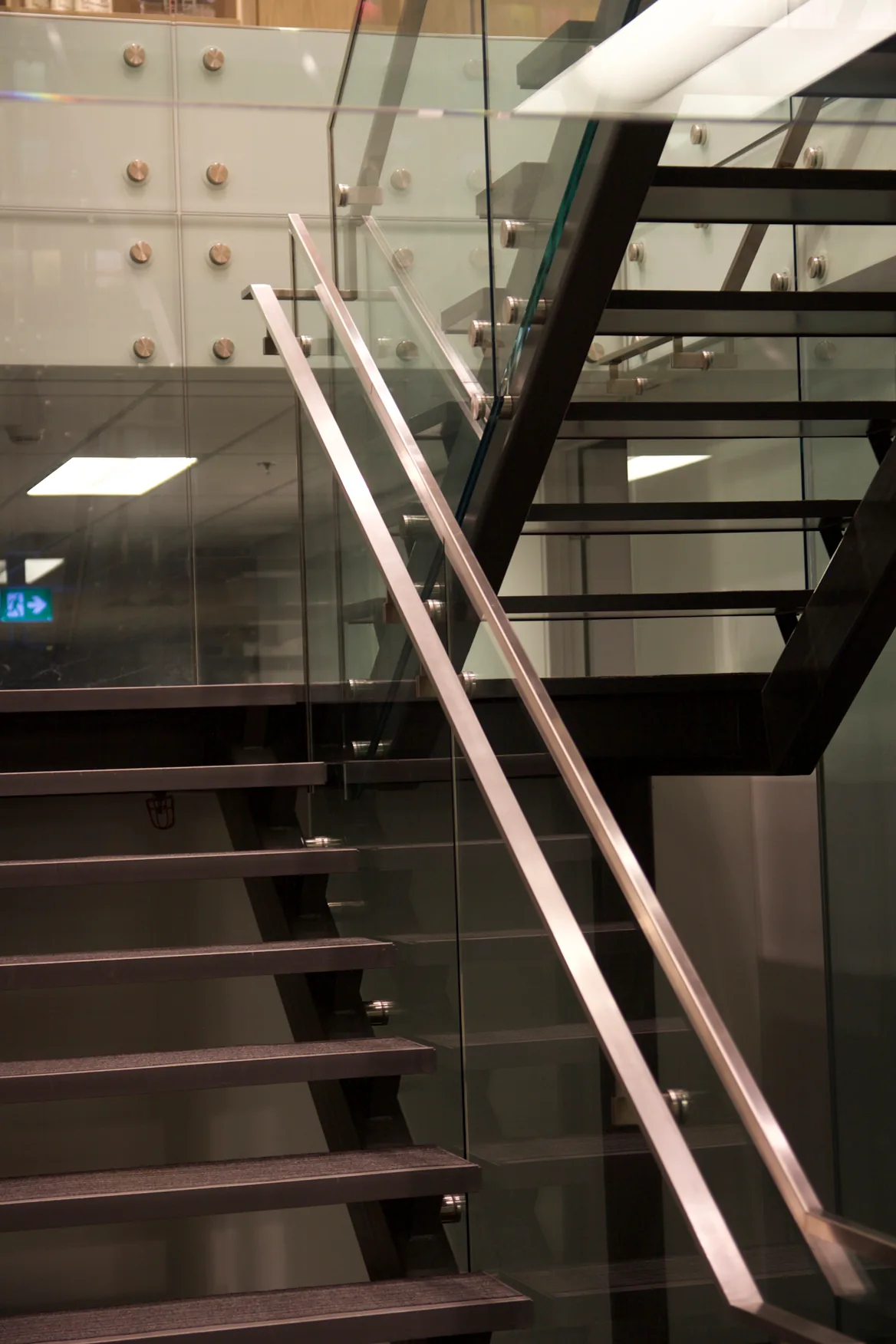 Penguin Stair: Open-riser steel stair with a glass guardrail and a stainless steel handrail