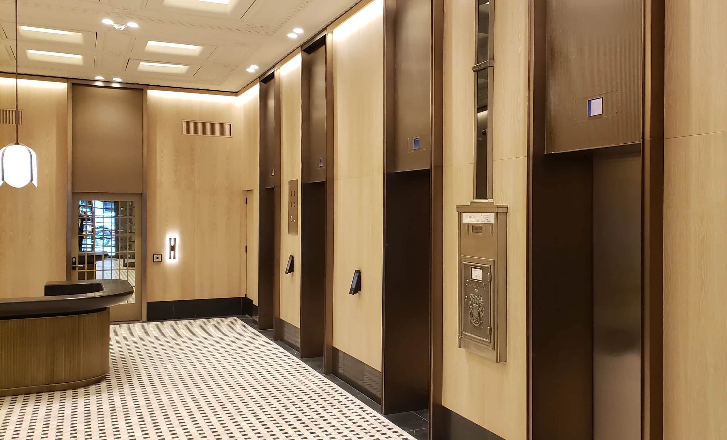 Richmond Elevator Lobby: Elevator lobby with dark bronze door surrounds and panels set between pale wood-grain walls