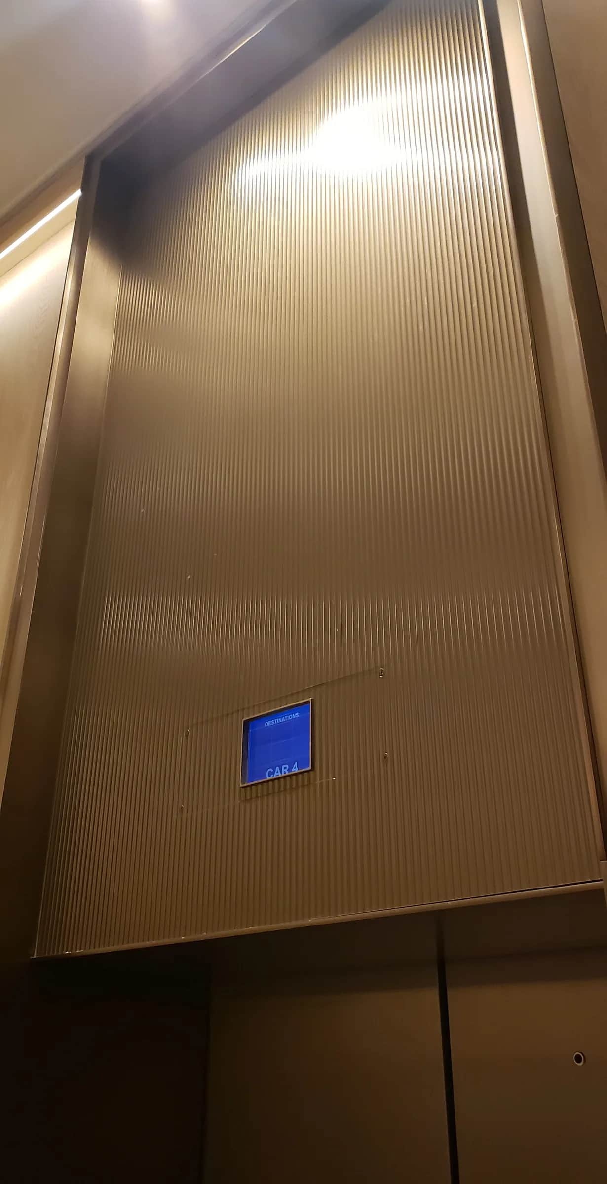 Richmond Elevator Lobby: Fluted bronze-finished panel above an elevator door, with a small destination display