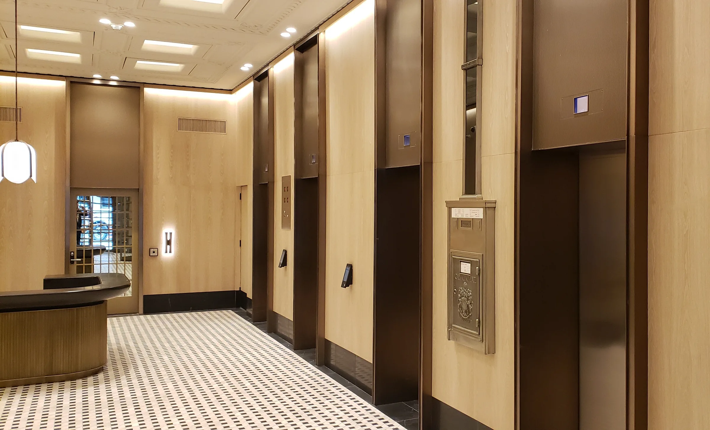Richmond Elevator Lobby: Elevator lobby with dark bronze door surrounds and panels set between pale wood-grain walls