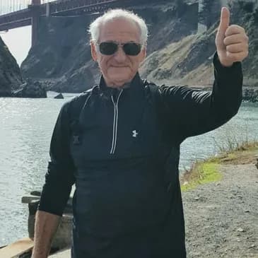George Klopot, in sunglasses, giving a thumbs-up by the water