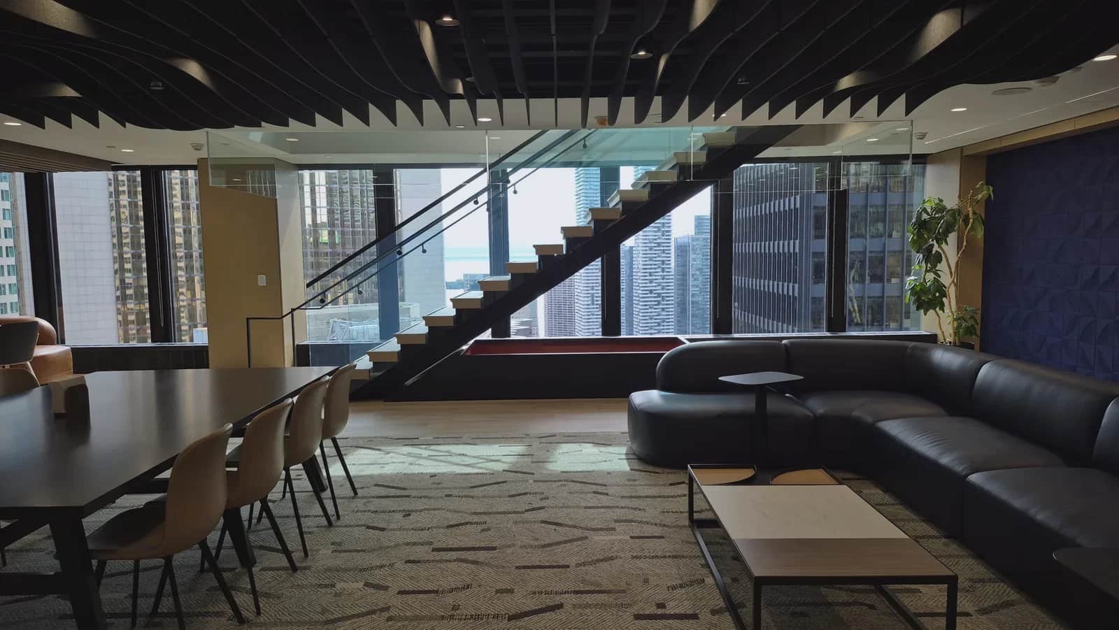 Office staircase, Toronto: Office meeting and lounge area with the floating glass-railed stair against the windows behind it