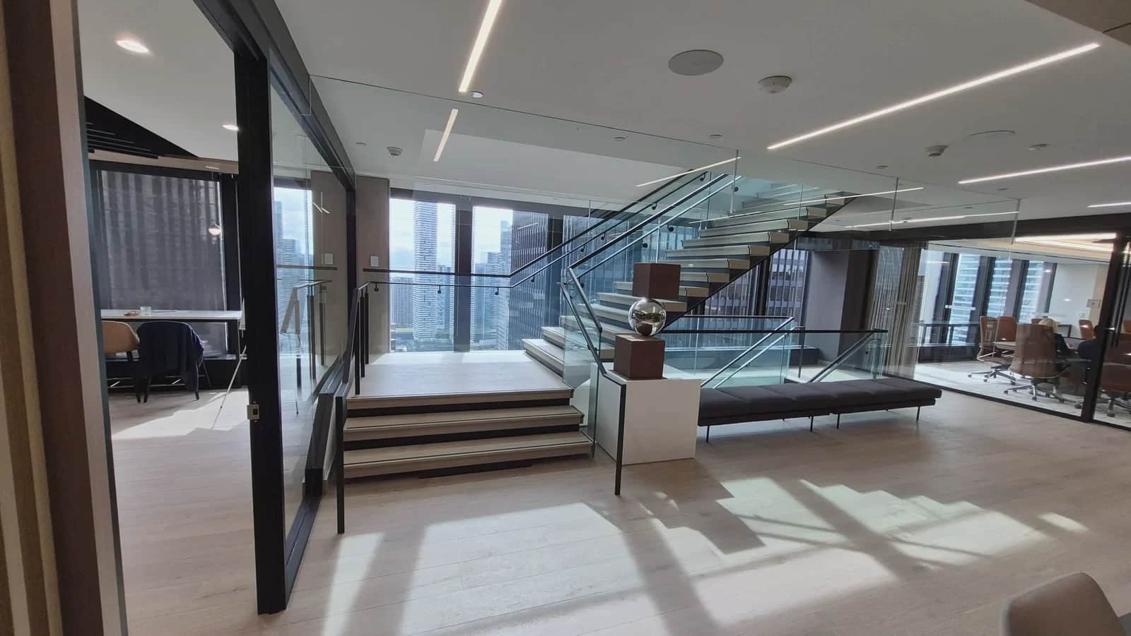 Office staircase, Toronto: Glass guardrails and the floating stair seen across an open office floor